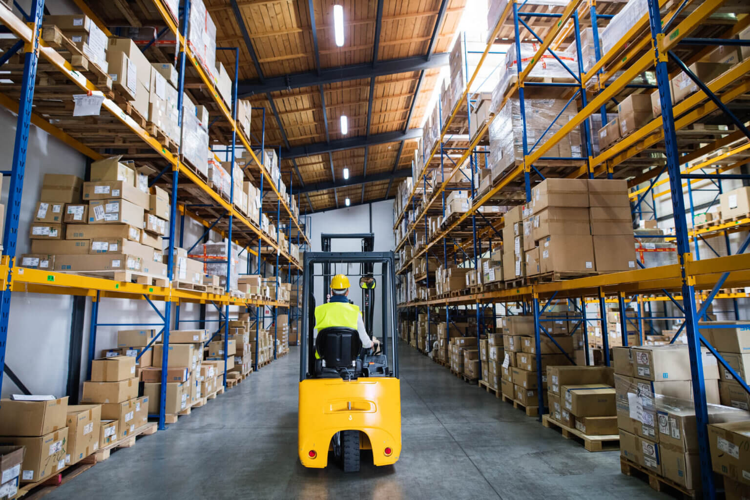 Forklift between racks in a warehouse / Wózek widłowy między regałami w magazynie