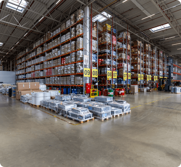 Pallets of goods stacked next to shelves in a warehouse / Palety towarów ułożone w magazynie obok półek